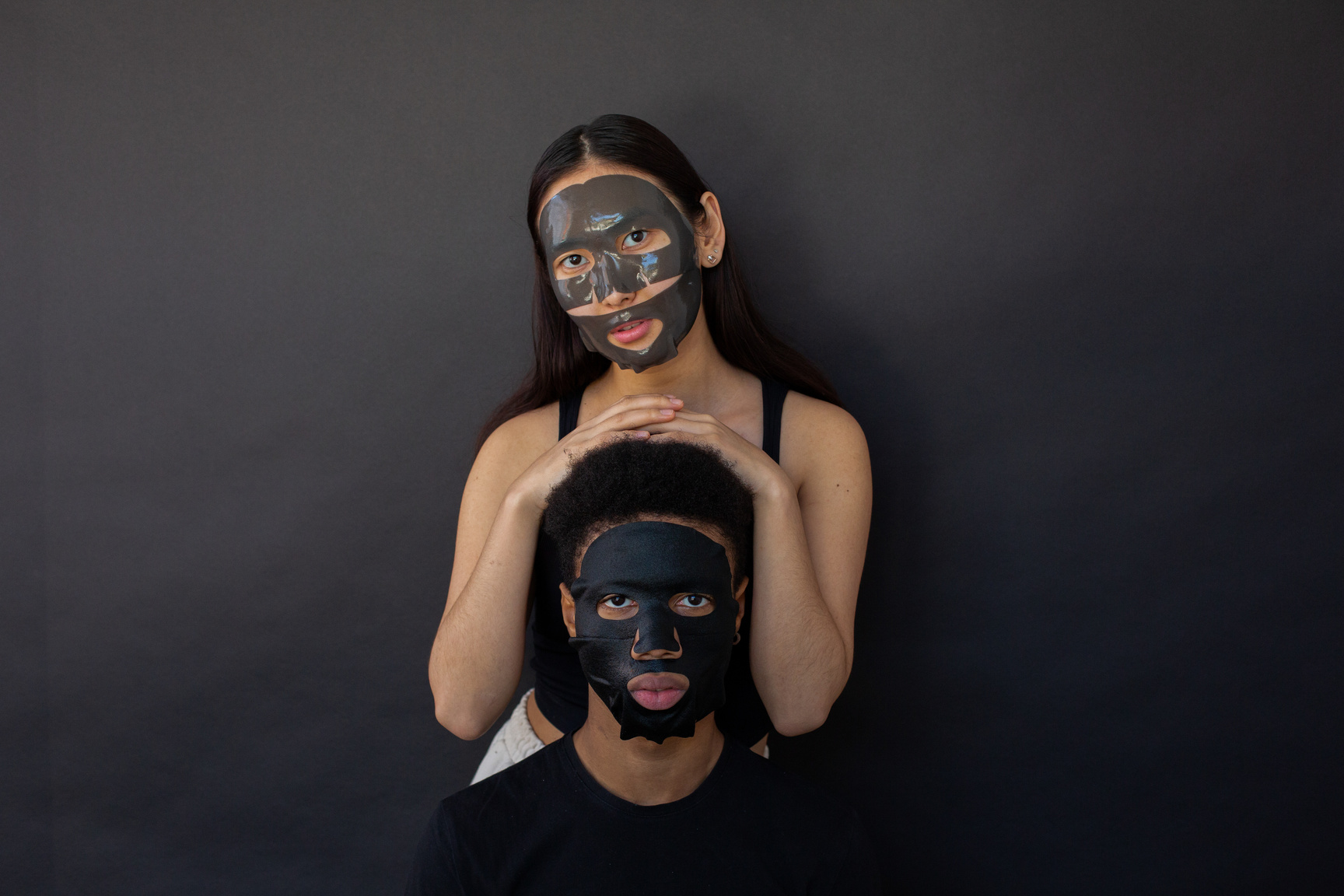 Diverse couple in sheet mask doing skin care procedure together